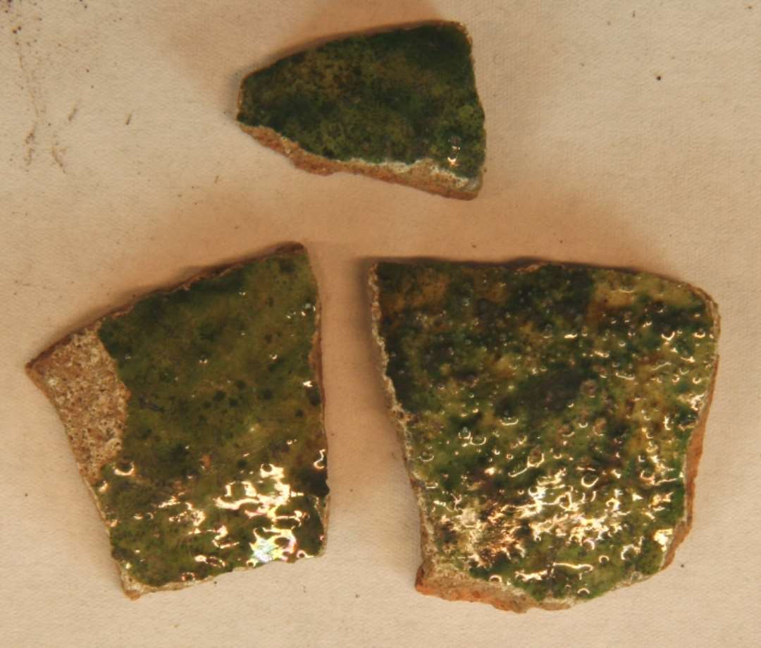 3 sideskår af rødbrændte kander med indvendig begitning og grøn glasur på     ydersiden. 
