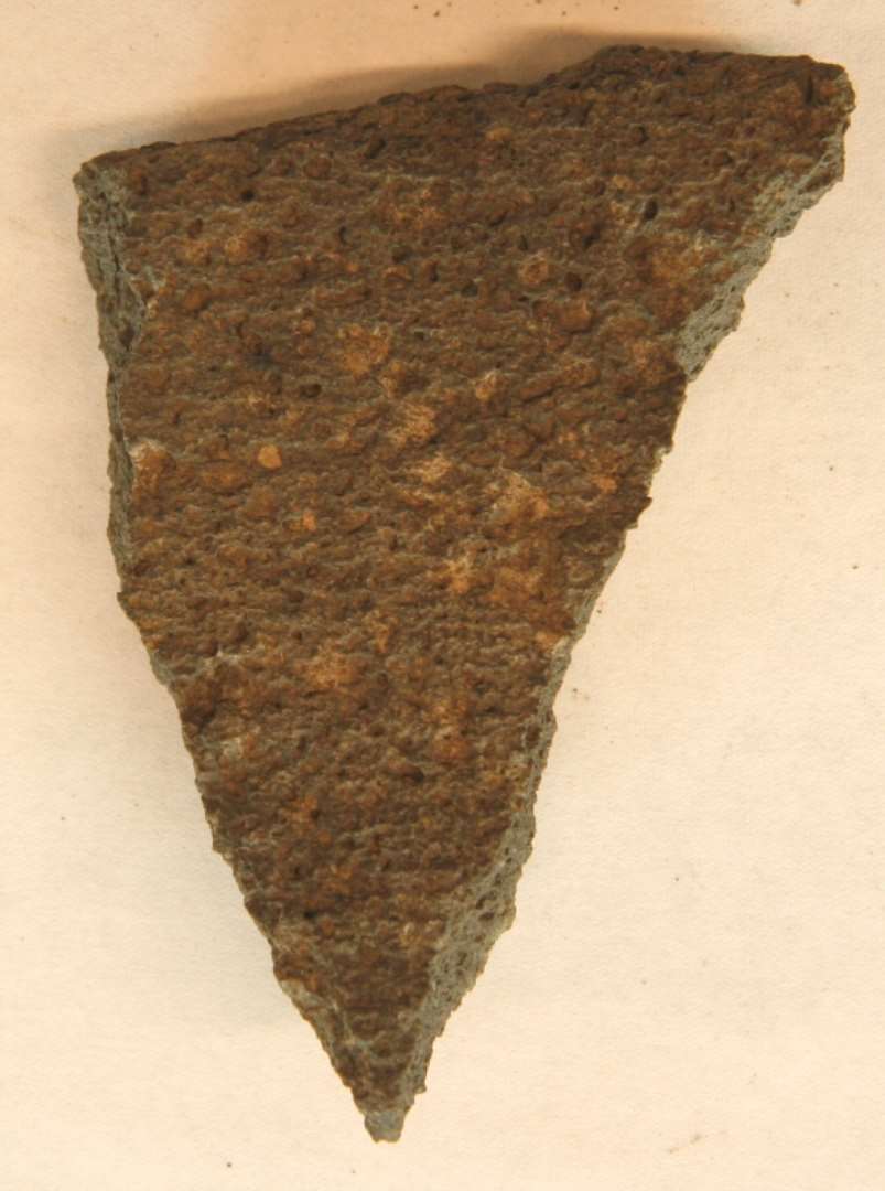 1 fragment af planslidt kværnsten af sortgrå basaltlava.