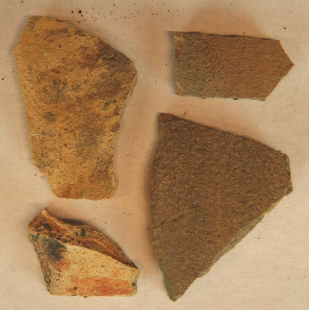 4 skår af Pingsdorf, deraf 1 fragment af tudfæste, gulligt med lys, rød bemaling, samt 3 sideskår med gullig til gråligt overflade. Det ene muligvis med en plet Lehmglasur, D1.