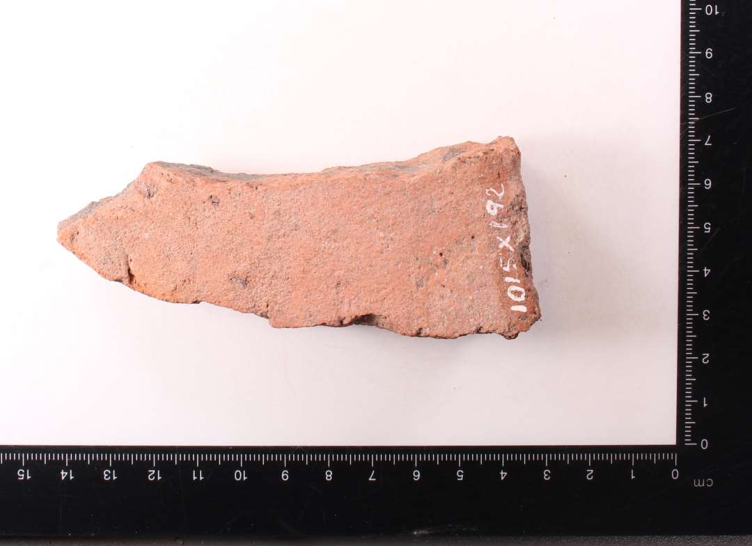 Fragment af kvadratisk, uglaseret gulvflise. Tykkelse: 2,5 cm.