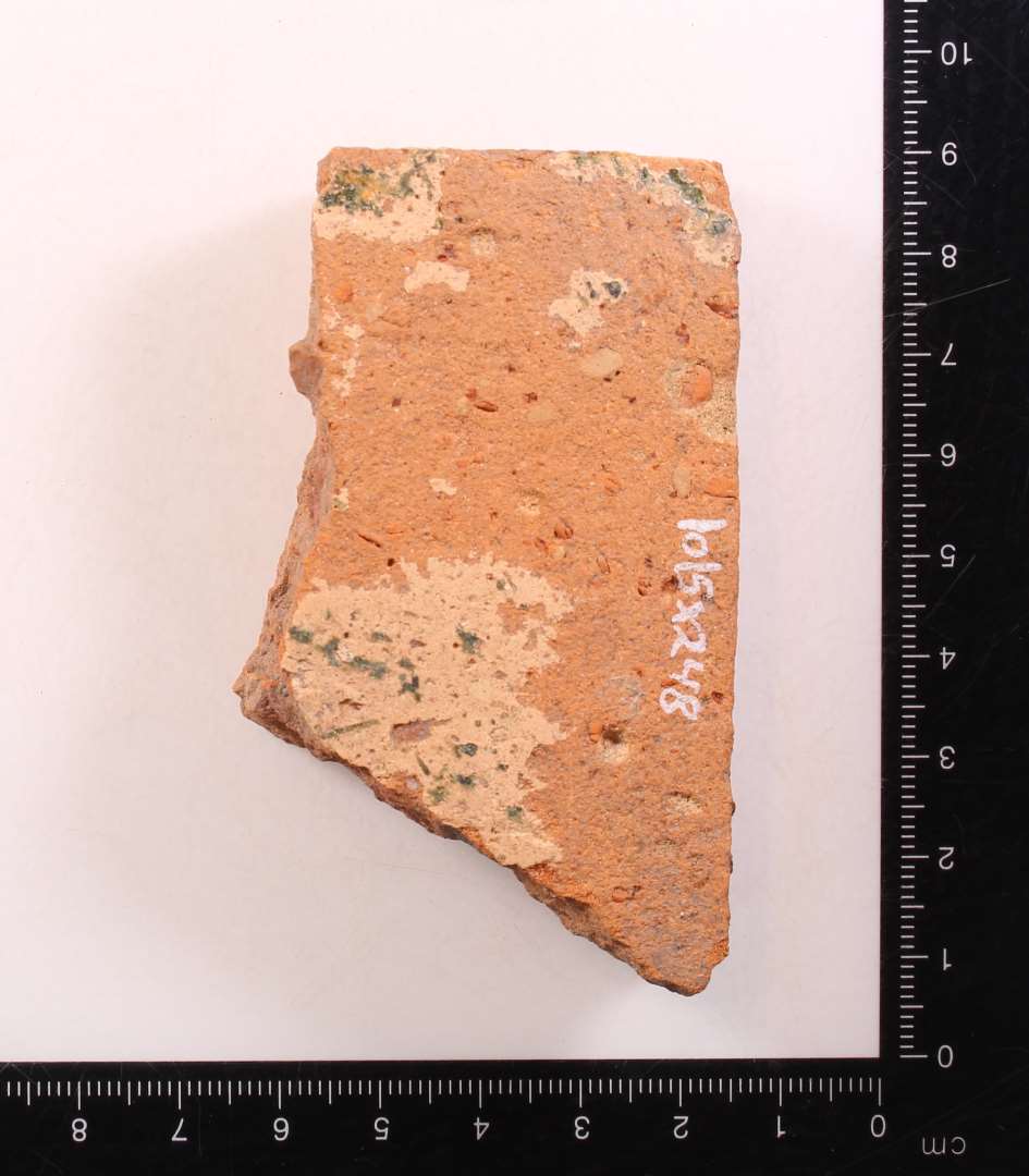 Fragment af gulvflise. Pibelersdekoration under glasurlag. Tykkelse: 1,5 cm.