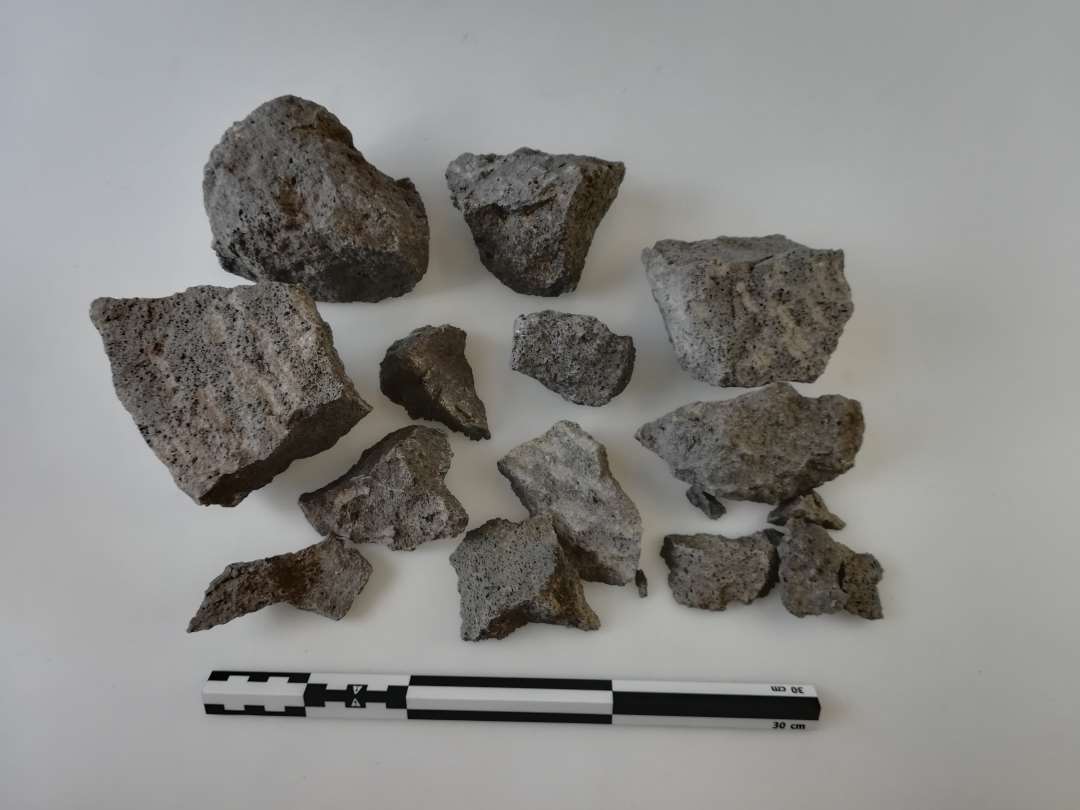 Fragmenter af kværnsten af basalt. Store og små stk. fundet samlet.  Spor efter hug på den ene side. Største tykkelse: 7,8 cm.