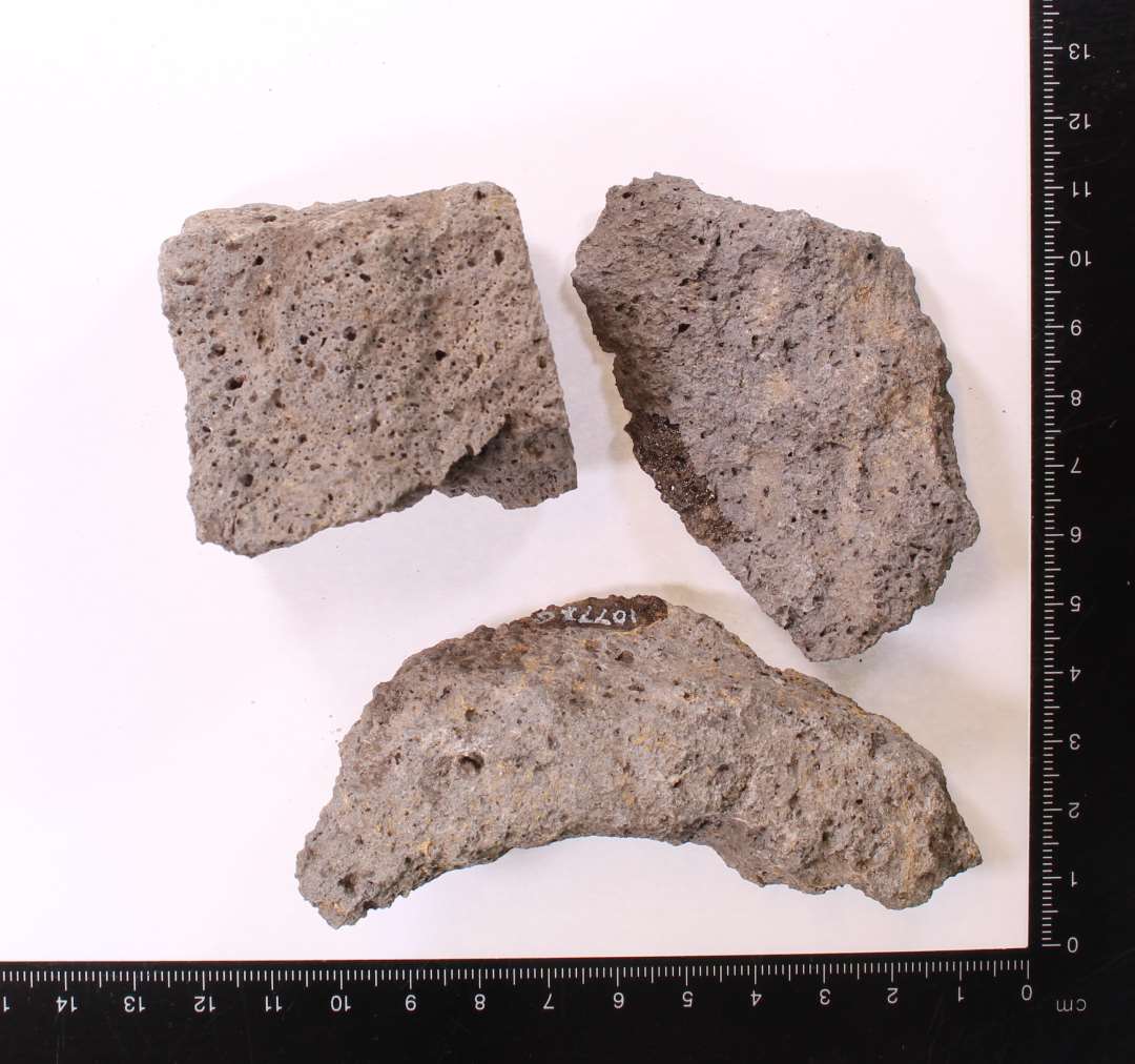 Fragmenter af kværnsten af basalt. Det ene stykke har del af vulst fra midterhul.