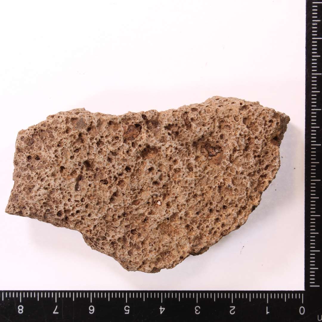 Fragment af kværnsten af basalt. Kraftigt slidt fragment, max.  tykkelse ca. 1,8 cm.