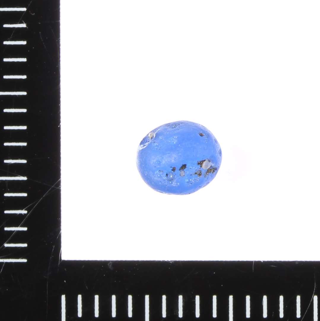 Lille rundsleben kugle i mat blå glas. Ca. 0,5 cm i diameter.