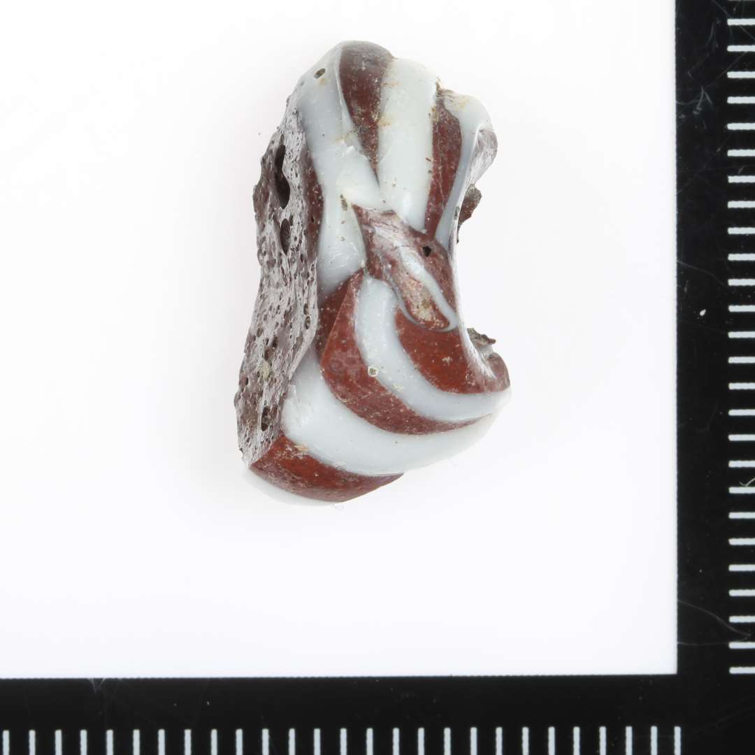 Fragment, Ugennemsigtig Rødbrun med hvide tråde.
Usædvanlig stor perle.