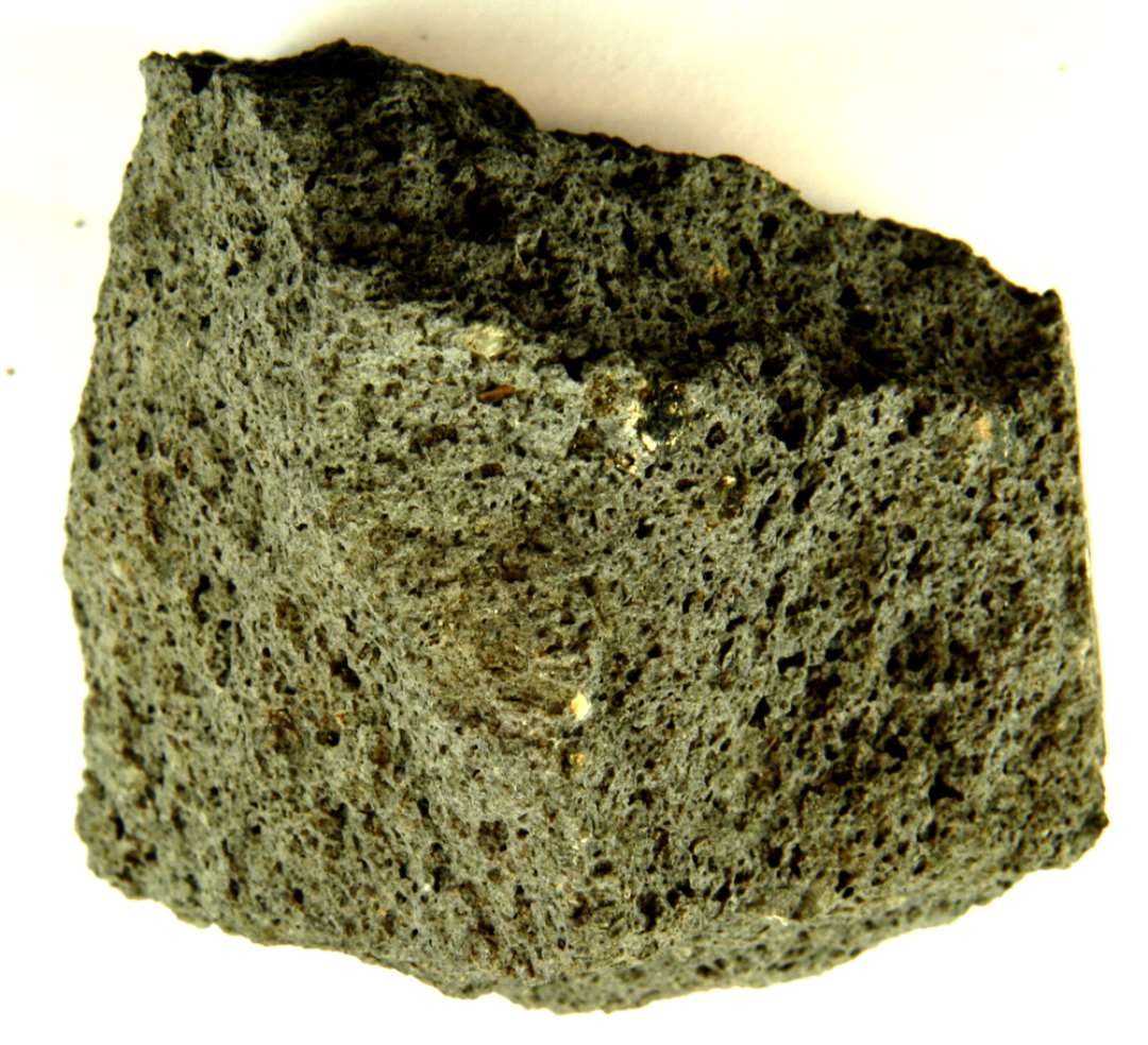 Fragment af rhinsk basaltlava af knytnævestørrelse. Et uregelmæssigt felt på ca. 2,5 x 4 cm. udviser en plan afslidt flade.