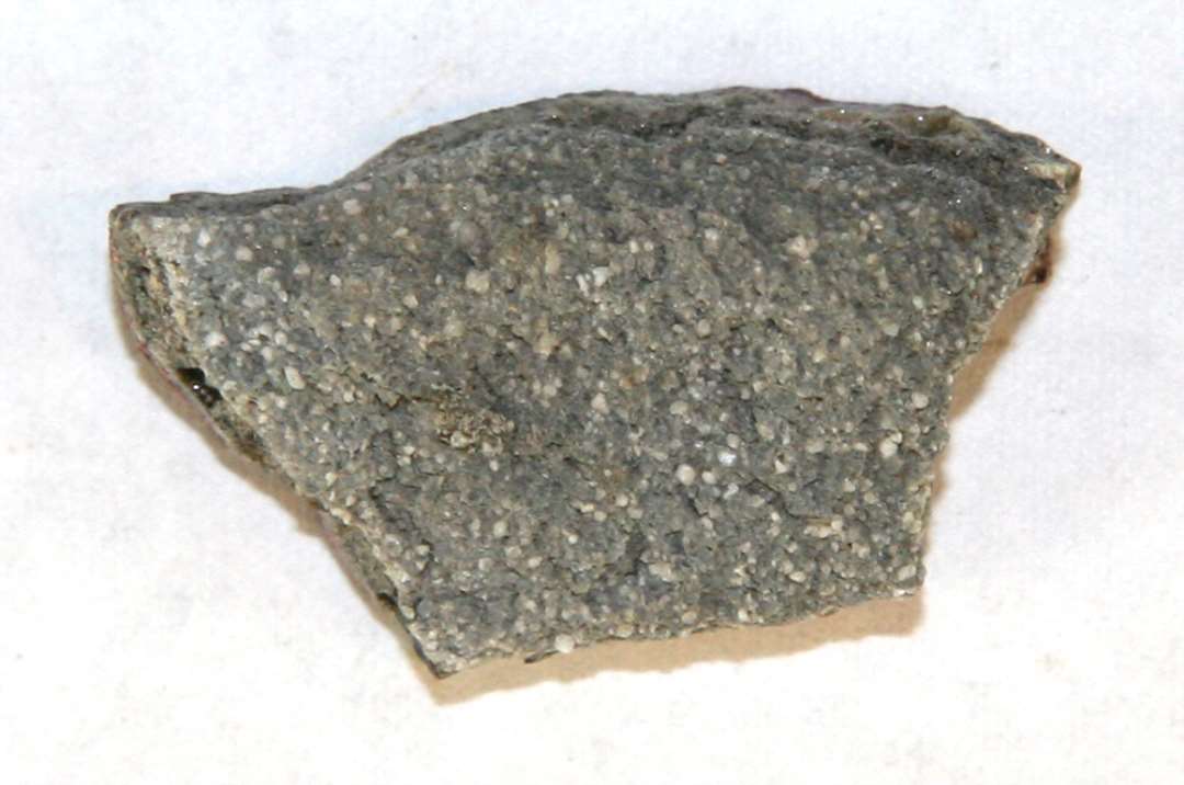 Bugskår af smeltedigel af porøst sandblandet gods, der på ydersiden er dækket af en sintret blærefyldt lerkappe, hvis overflade fremtræder som et glasuragtigt zinnoberrødt lag.