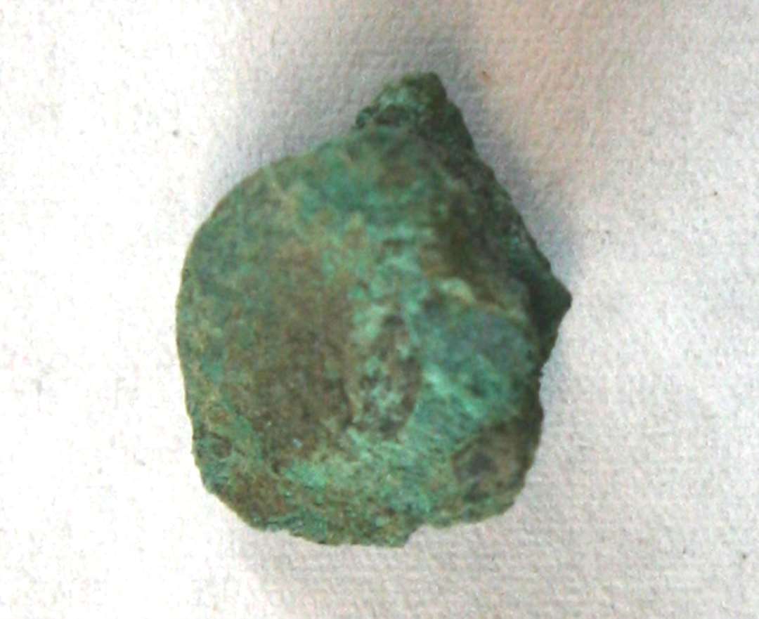 1 irbelagt bronzestump af form som et uregelmæssigt sømhoved,  ca. 1,3 x 1,6 cm. Tykkelse: ca. 0,75 cm.