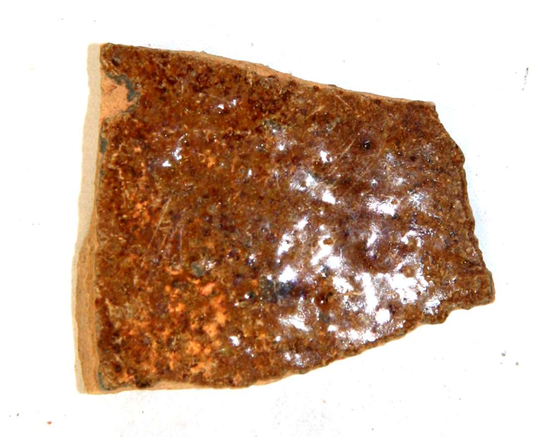 1 sideskår af rødbrændt lergods med klar blyglasur på ydersiden.