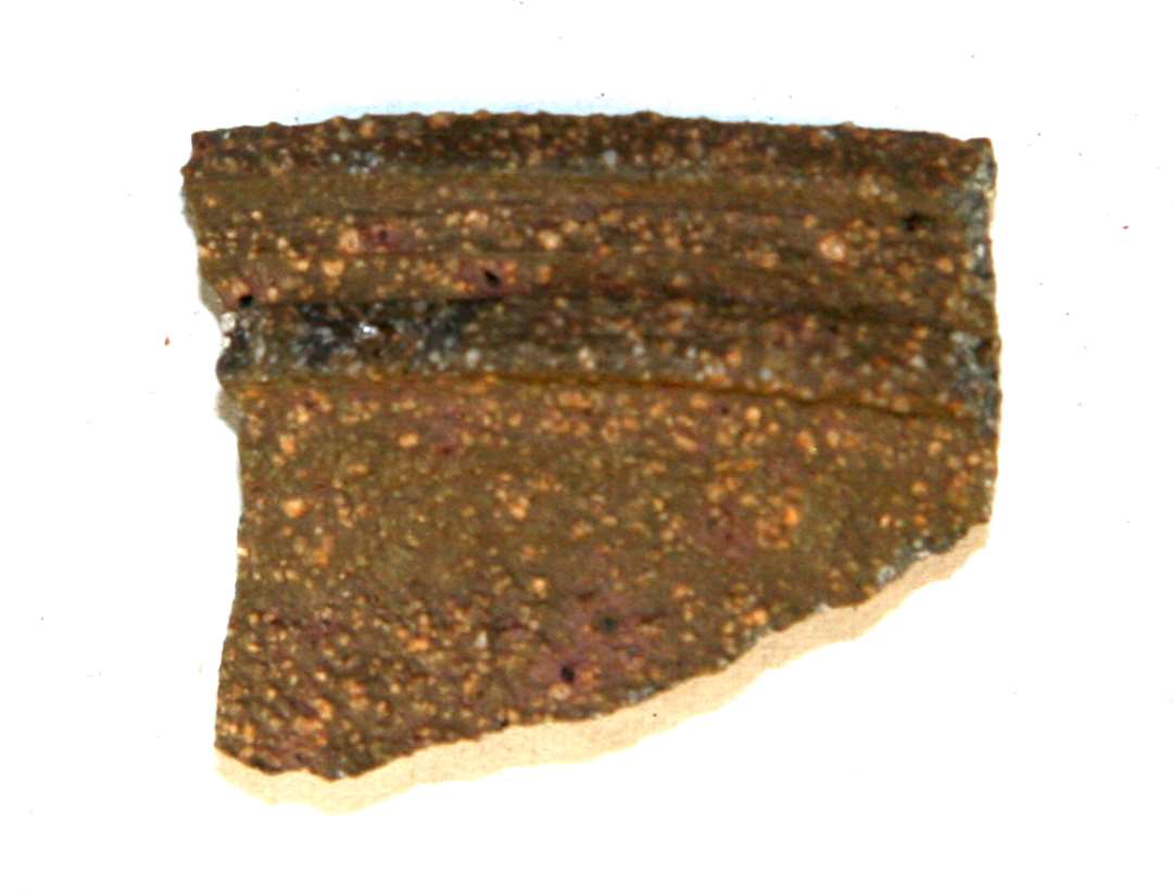 1 halsskår af gråbrunlig grynet stentøj fra kar (kande) med kantede, fremstående vulster og furer på ydersiden.