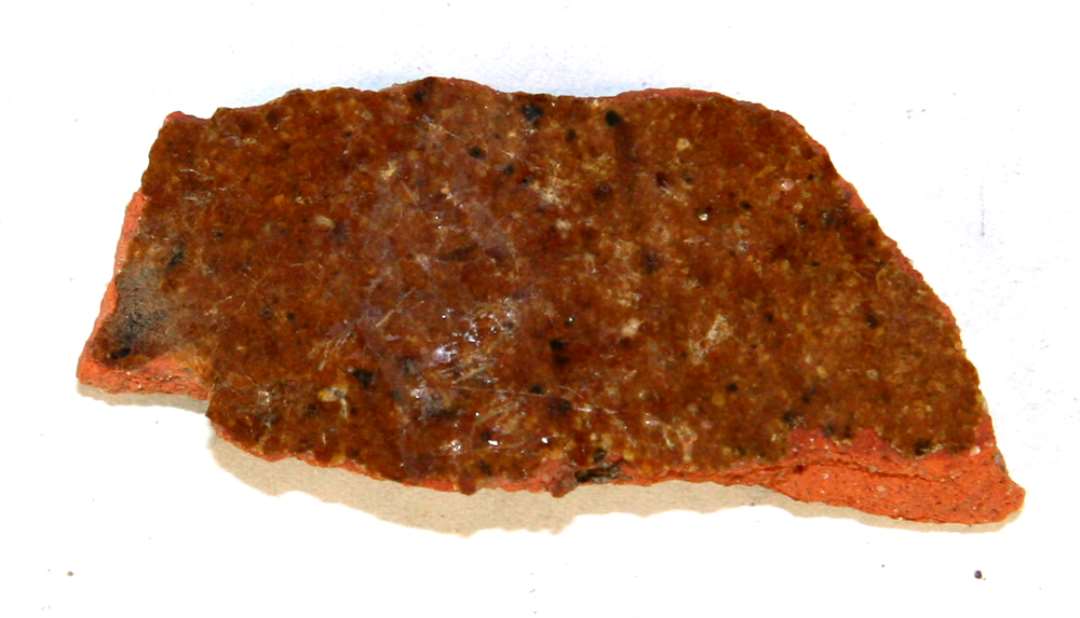 1 sideskår af rødbrændt lergods med klar blyglasur på ydersiden og delvis på indersiden.