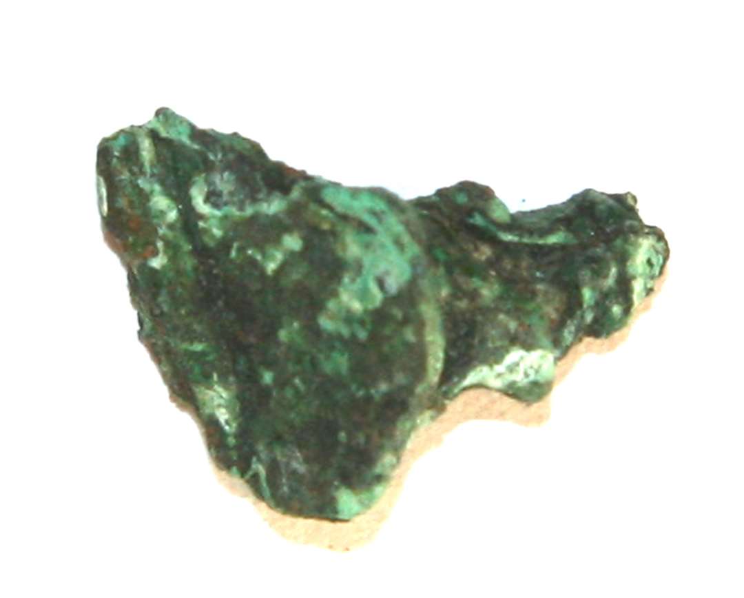 Irbelagt bronzestump af form omtrent som et sømhovede med en hossiddende stump af den afbrudte stift. Længde: ca. 1,8 cm.