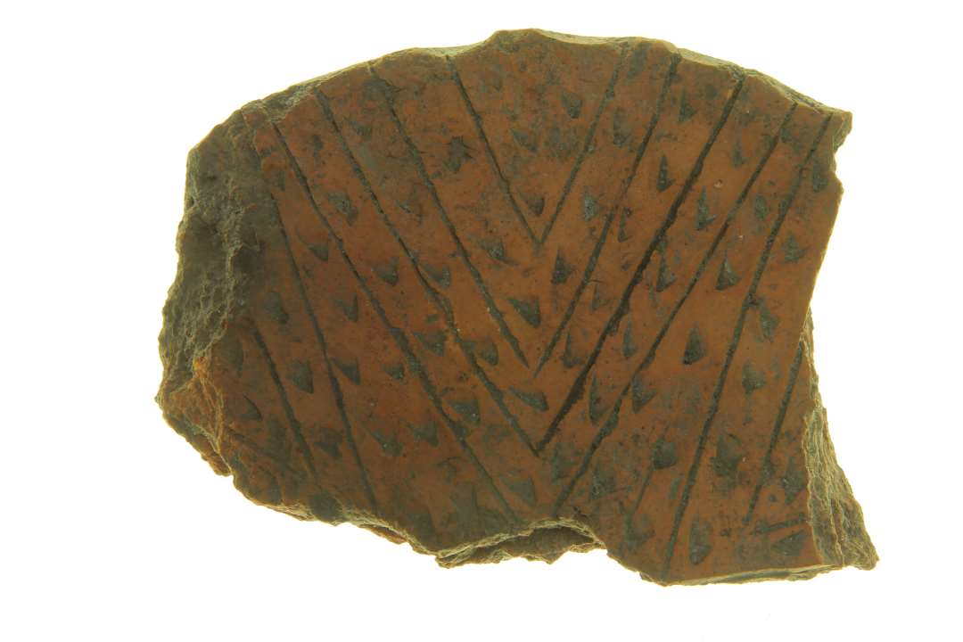 Fragment af låg med dekorationsborter i form af takker og indhak. Oprindelig diameter: ca 20 cm.