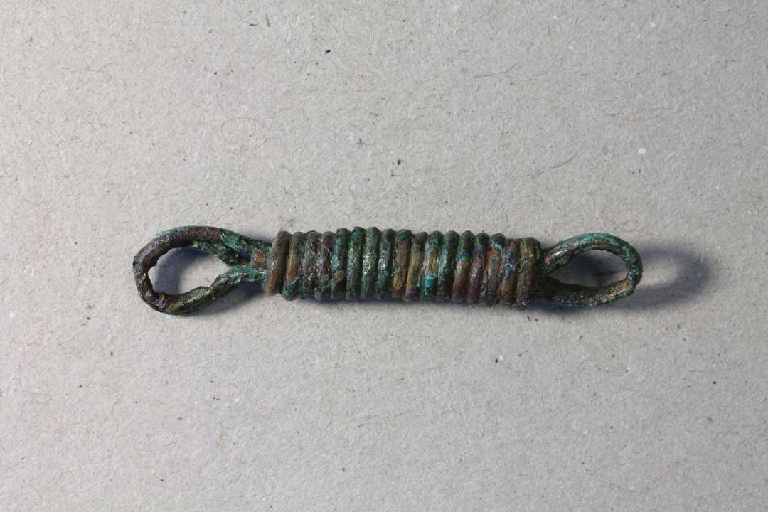 Svirvel eller et kædeled fremstillet af omviklet bronze/kobbertråd. Sands. samhørende med x678. Der kan være tale om et såkaldt 'geddeforfang'. Længde: 4 cm.