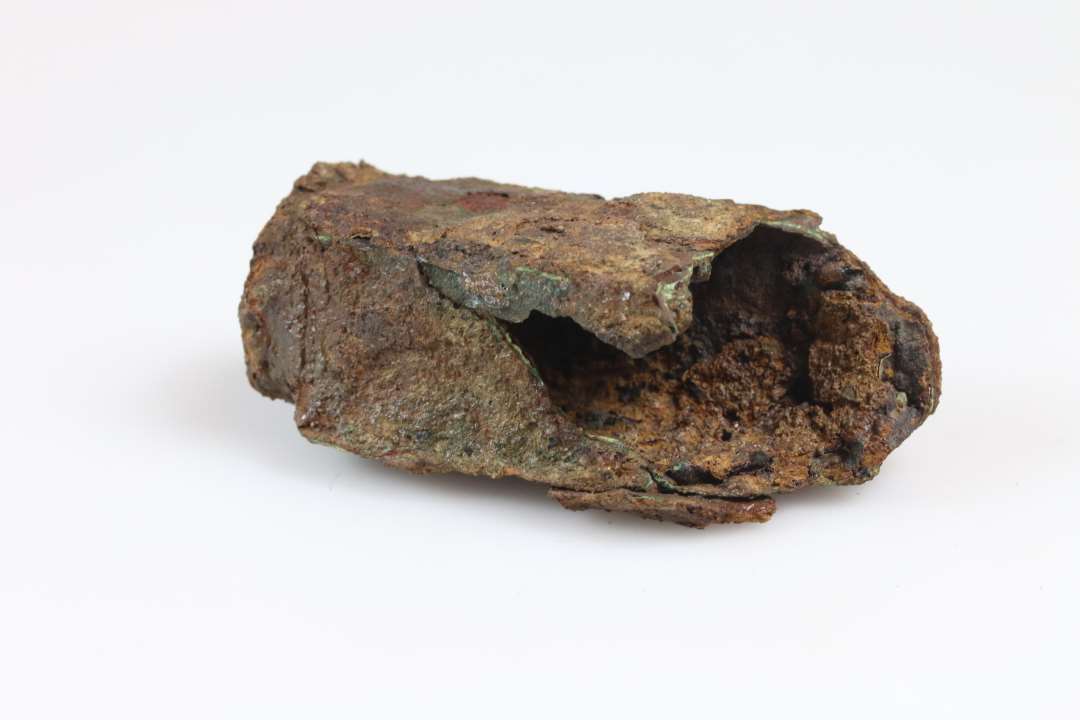 Fragment af låsehus. Jern og bronzeindhold. Største mål: ca 6,5 cm., Konserveret