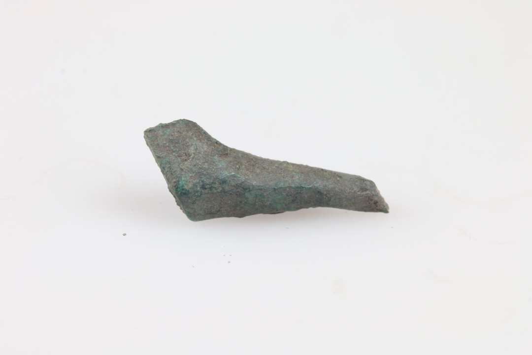 Kræmmerhus foldet af rhombeformet stykke bronzeblik. Mål: 2,1 cm., Ukonserveret. 