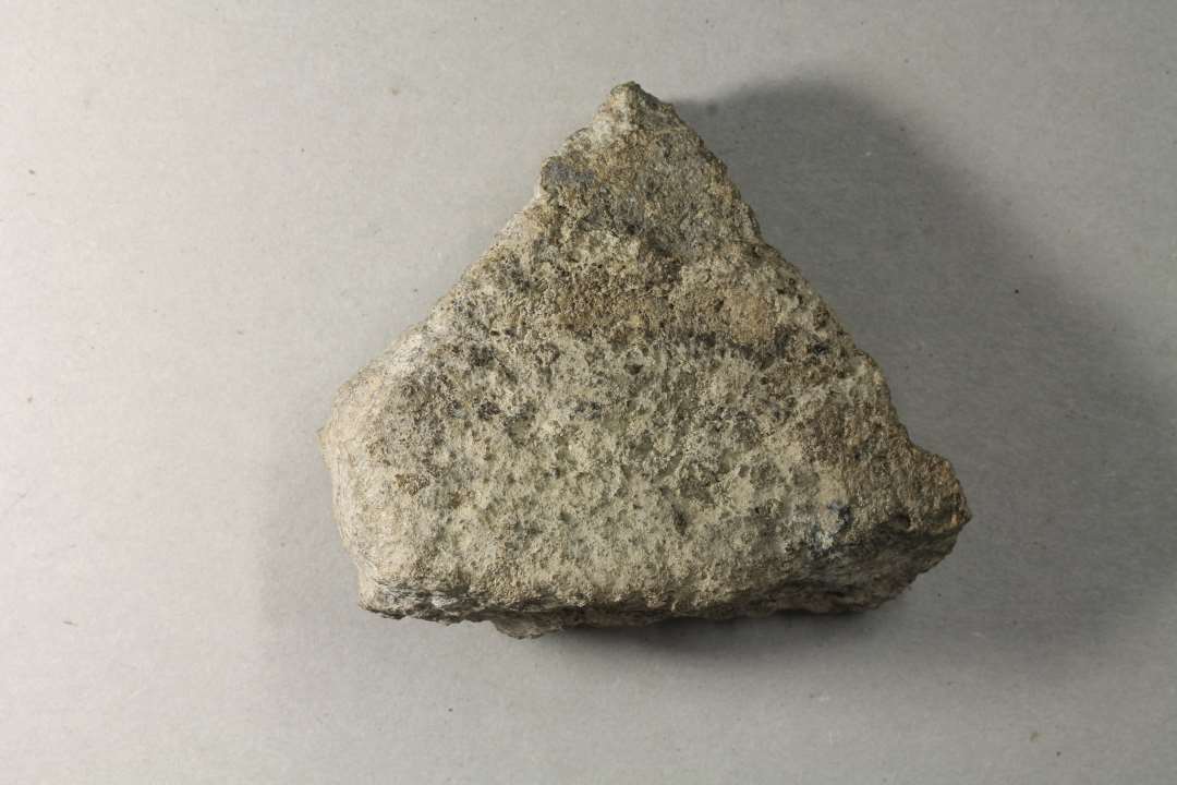 Fragment, ca. 8 x 10 x 4 cm m. høj vægtfylde og hvidlig korrosion. Affald fra en eller anden proces med bly.