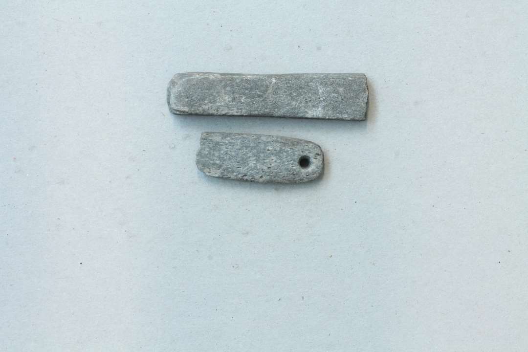 2 fragmenter af hvæssesten, det ene med et hul i den ene ende. 1. længde ca. 7 cm. tværsnit ca. 1,5 x 1 cm. 2. længde 4 cm., tværsnit ca. 1,5 x 0,5 cm. 