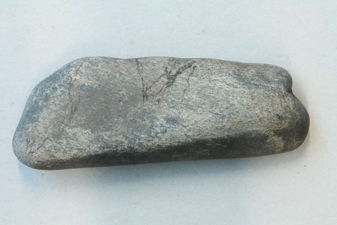 Aflang sten m. to meget glatte sider. Kan have været anvendt som sømglatter måske. Mål længde ca. 16 cm., bredde ca. 6 cm. 