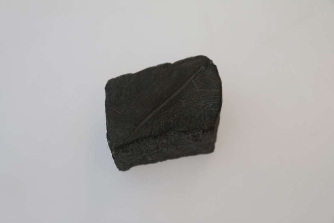 Fragment af støbeform i sten med to pashuller. Borthugget (centralt?) parti. På den anden side sliberidse, måske fra slibning af nåle. Mål: 5,2x4,3x2,9 cm. Mørk kalksten?