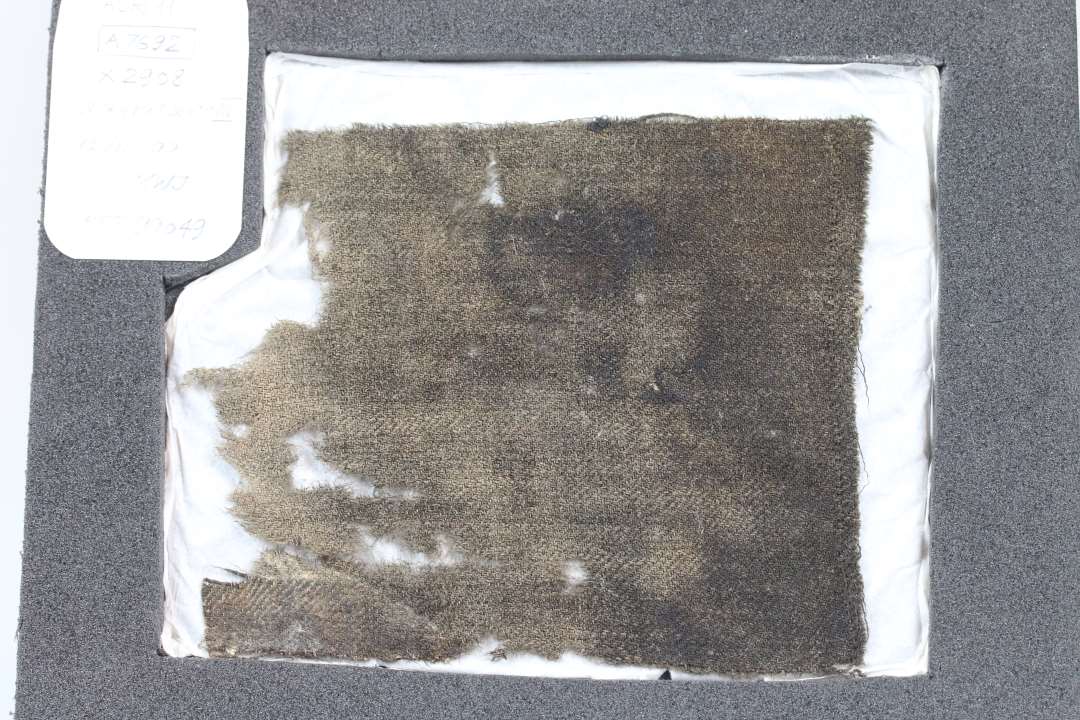 Et stykke vævet tekstil. Uld. Ca. 10 x 15 cm.