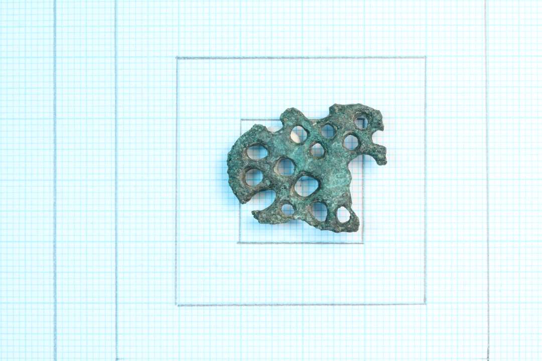 Større fragment af Urnesfibel, ca. 2 x 3 cm. Kons.  Identisk (samme form) med spændet ASR1021x23, Type m. tværstreger før tre små kløer