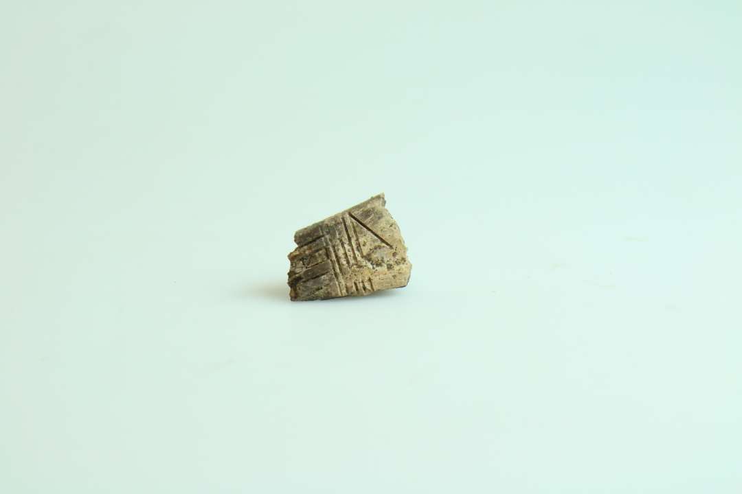 Lille fragment af langtandskam med ornamentik, fragmenteret. Største mål ca. 2,5 cm.