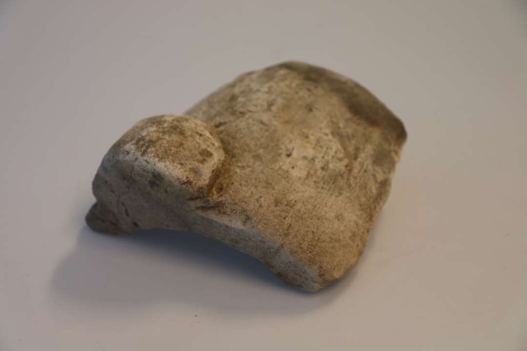 Stort fragment af stenmorter m. rand, greb og stort set hele siden. Udvendig ses lodret riffelhugning. 17,5x19 cm.