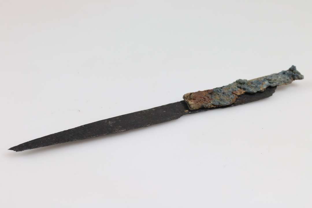 Knivsblad med angel og delvist bevaret håndtag af jern/bronze?, ca. 14,2 cm langt.Samlet længde: 15,5 cm., Konserveret