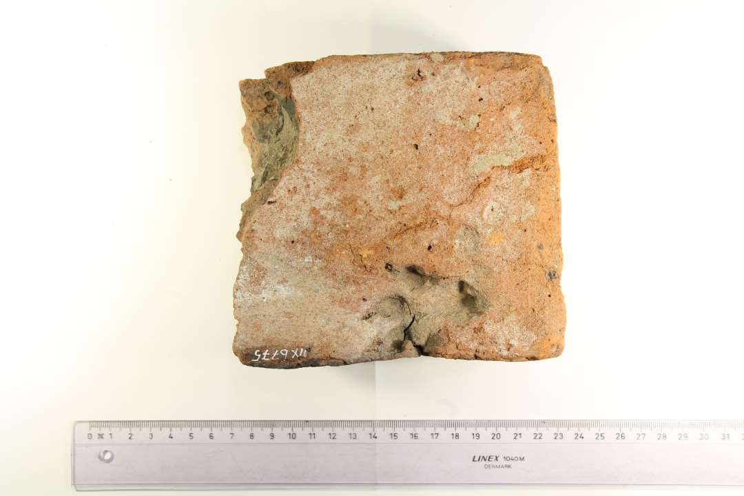 To fragmenter af munkesten. 1 med dyrespor, hundepote?  og 1 med indridsninger. Mål henholdsvis ca. 17 x 13,5 x 6,5 cm., og ca. 13 x 12,5 x 7,5 cm.