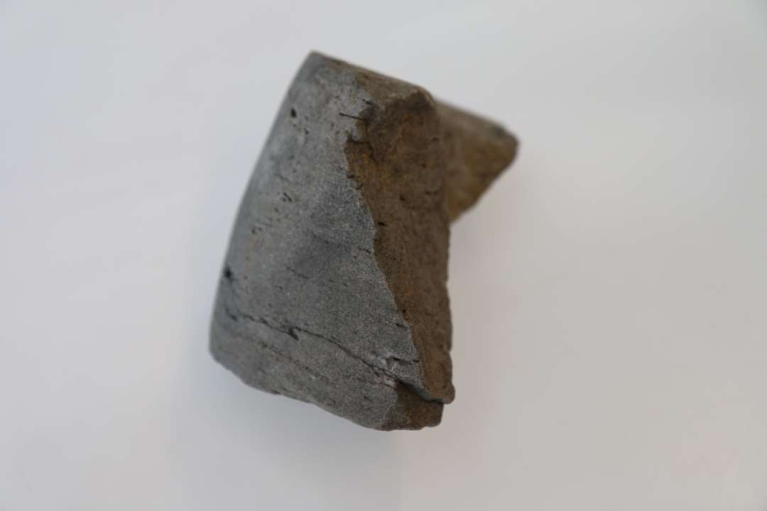Fragment af en roterende slibesten. 11,5 cm bred og ca. 20 cm ø af en tæt sandsten. 