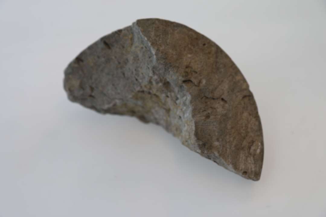 Fragment af en roterende slibesten. 11,5 cm bred og ca. 20 cm ø af en tæt sandsten. 