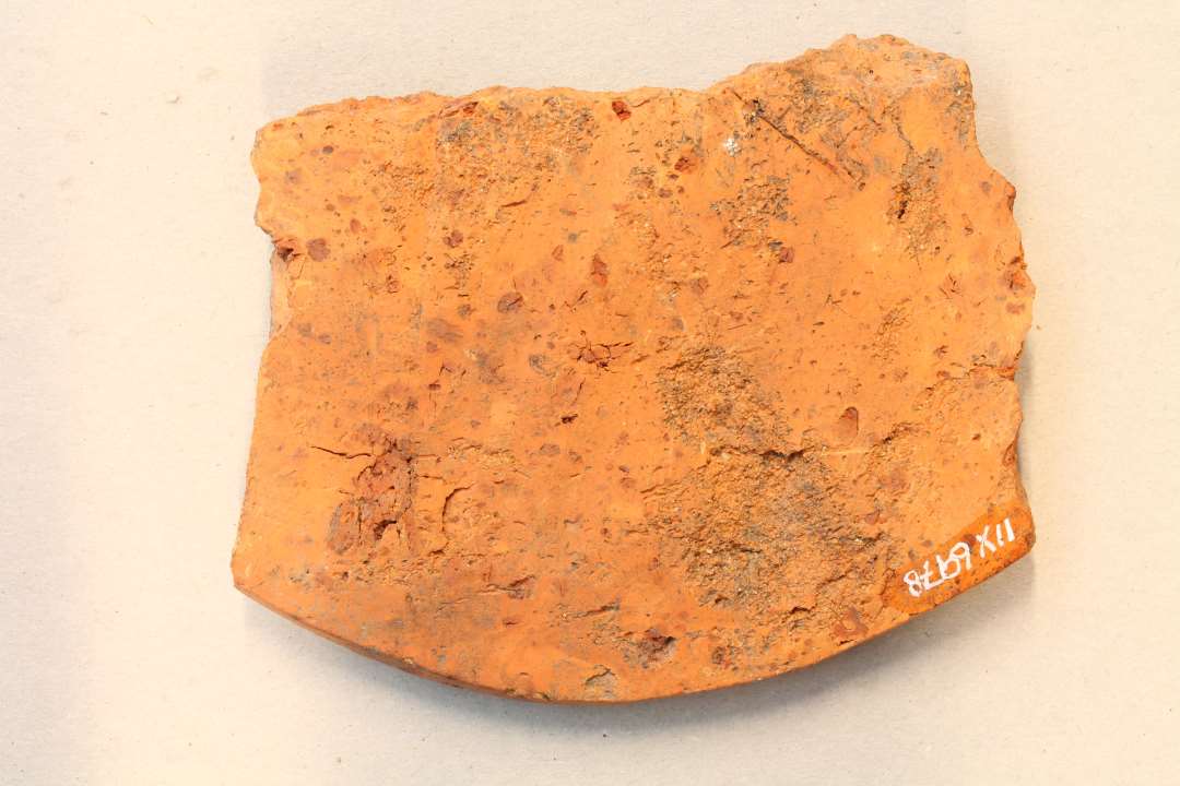 Fragment af låg med stregornamentik. Største mål 9 cm.