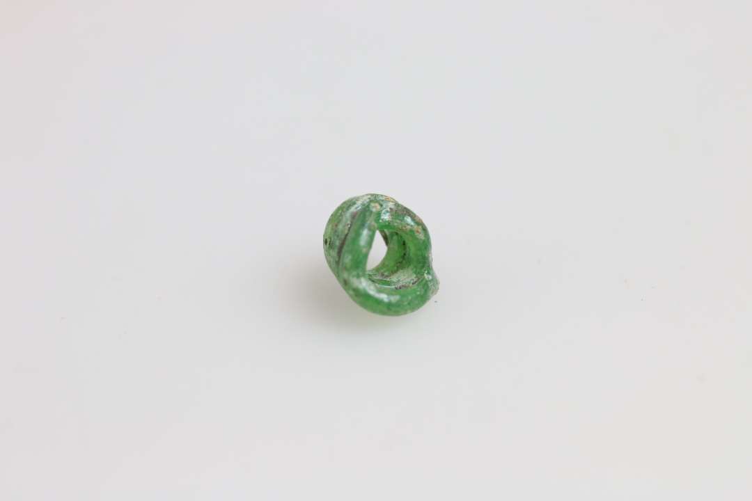 Glastråd pølset op til noget der ligner en perle. Grønt, ret klart glas. Største mål: ca 0,7 cm.