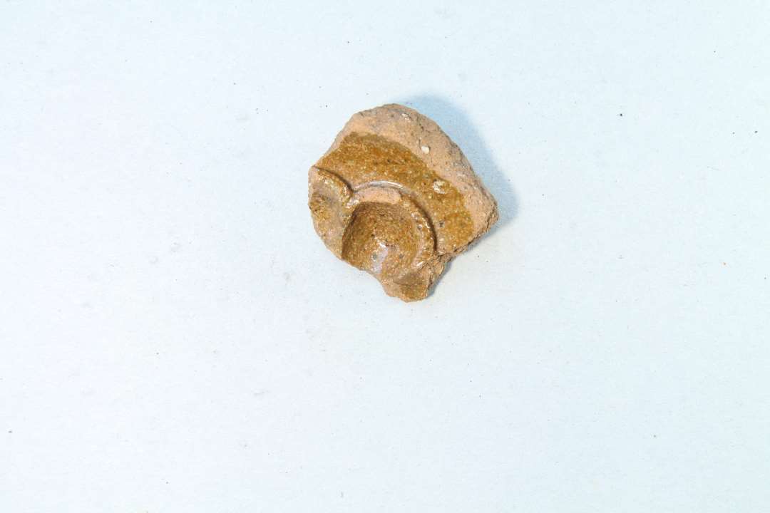 Fragment af medalionkakkel med blomsterdekoration skabt vha. fingerindtryk. Se også x1091,  x8005 og x8006. Fragmenterne fra de nævnte x-numre stammer formodentlig (2 af stykkerne passer sammen)  fra samme kakkel.