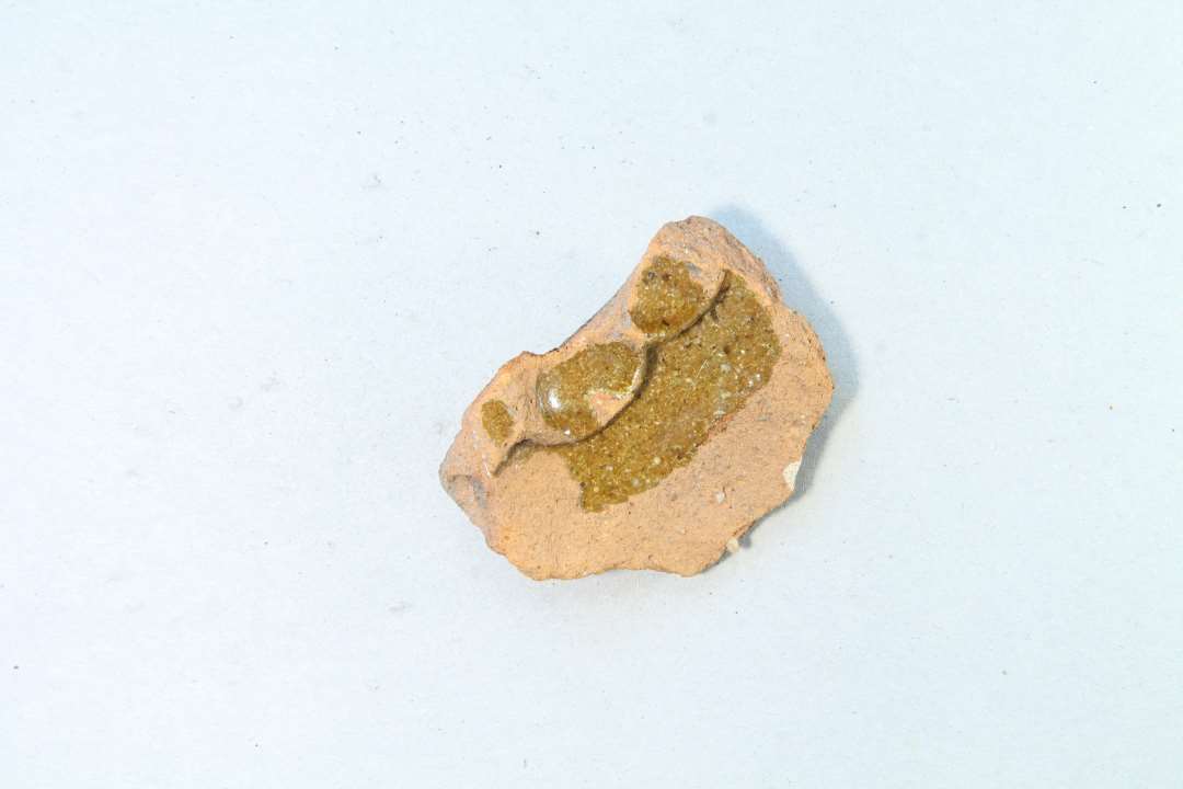 Fragment af medalionkakkel med blomsterdekoration skabt vha. fingerindtryk.