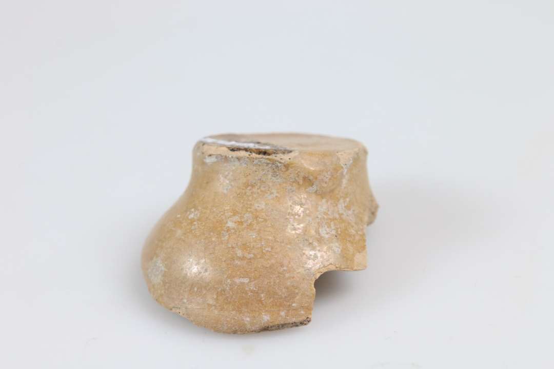 Skår af fladbundet miniature lerkar/salvekrukke/rangle, lysorange gods og klar glasur. Bunddiameter: 2,5 cm.