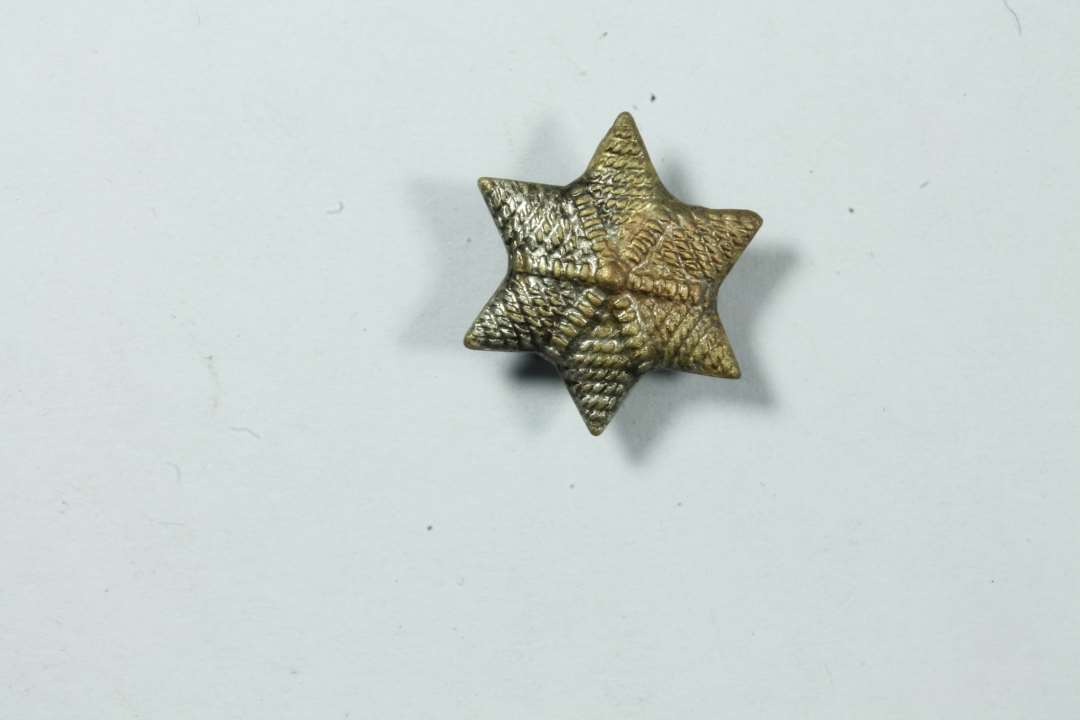 Lille metalstjerne (seks ender) med en diameter på 11 mm. En såkaldt årsstjerne, anvendt af bl.a. KFUK-spejderne i 1960-70erne.