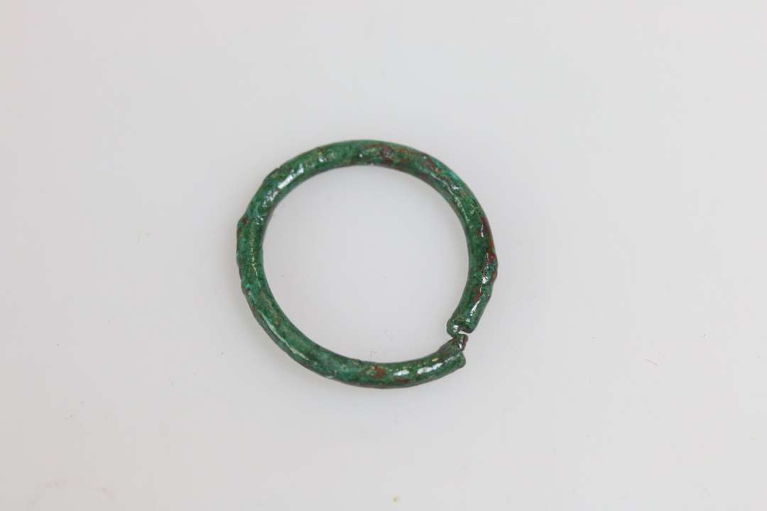 Ringspænde? Bronzering med trindt tværsnit. Diameter: ca 2,2 cm. Brækket ved tornfæstet?, som er en indsnævring af ringen.