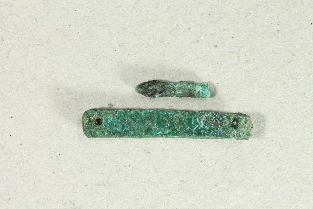 Bronzebeslag med 2 huller. Største mål: 2,5 cm., samt lille bronzestump