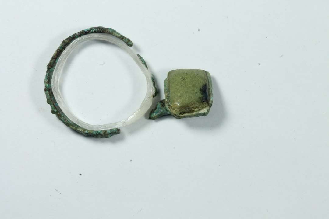 Fingerring med gulgrøn (glas?) sten. Ydre diameter: ca 2,1 cm.