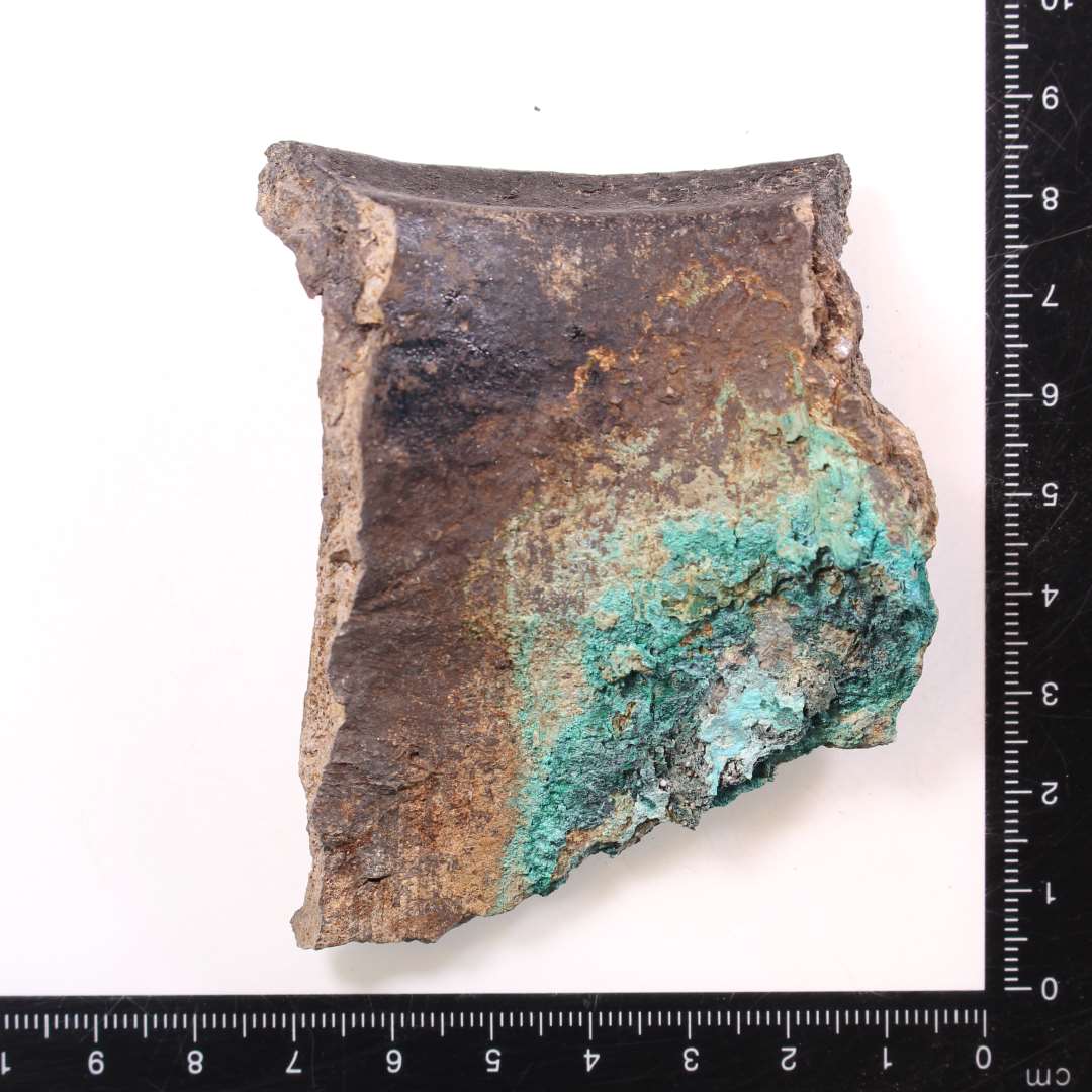 Randskår af kuglepotte med belægning af kobberlegering/bronze på indersiden.