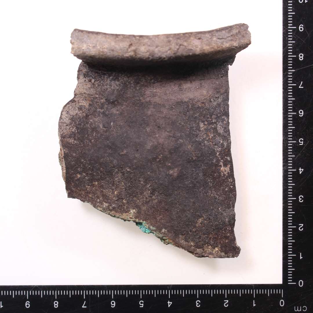 Randskår af kuglepotte med belægning af kobberlegering/bronze på indersiden.
