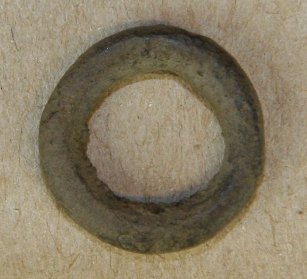 En lille, kraftig ring af kobberlegering. Ydre diameter: 15 mm. Snøremalle?