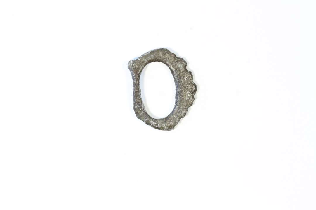 Fragment af lille spænde, måske dobbeltspænde af kobberlegering. Mål: 13x17 mm