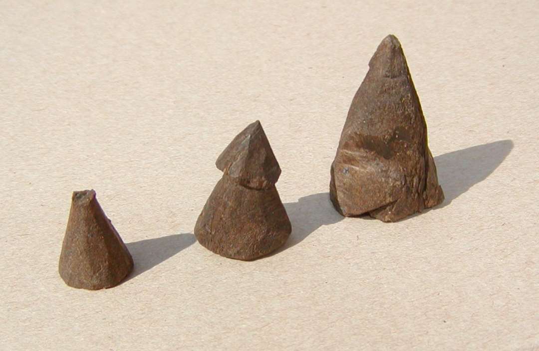 Tre kegleformede spillebrikker, en med afbrækket top, h. 1,8 cm, en med top, h. 2,5 cm og én uden top, h. 3,5 cm (forarbejde?), 
