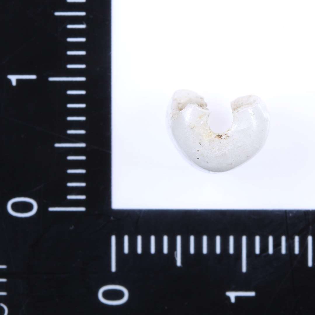 Fragment af velbevaret, cylindrisk perle af hvidt uigennemsigtigt glas. H 7 mm, ø 8 mm.