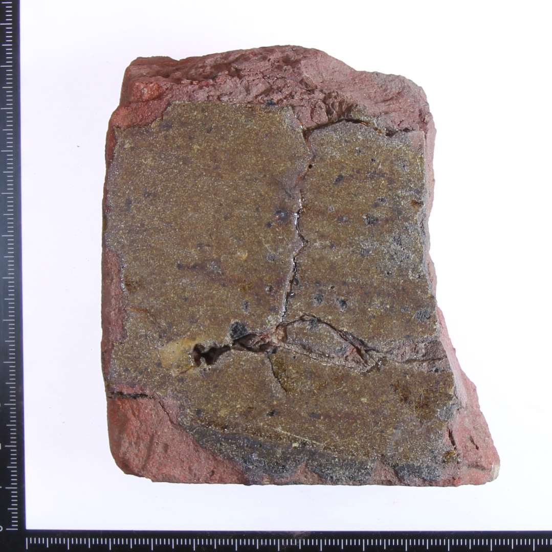 Fragment med brunlig glasur, største længde 11 cm, tykkelse 3 cm.