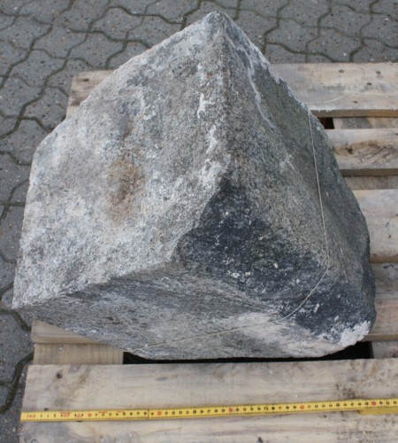 Søjlesokkel af mørk gråblå granit. Største mål: 45 x 31 x 31 cm. Tilhuggede tilnærmelsesvis glatte flader på fire sider. Ene hjørne er brudt af.